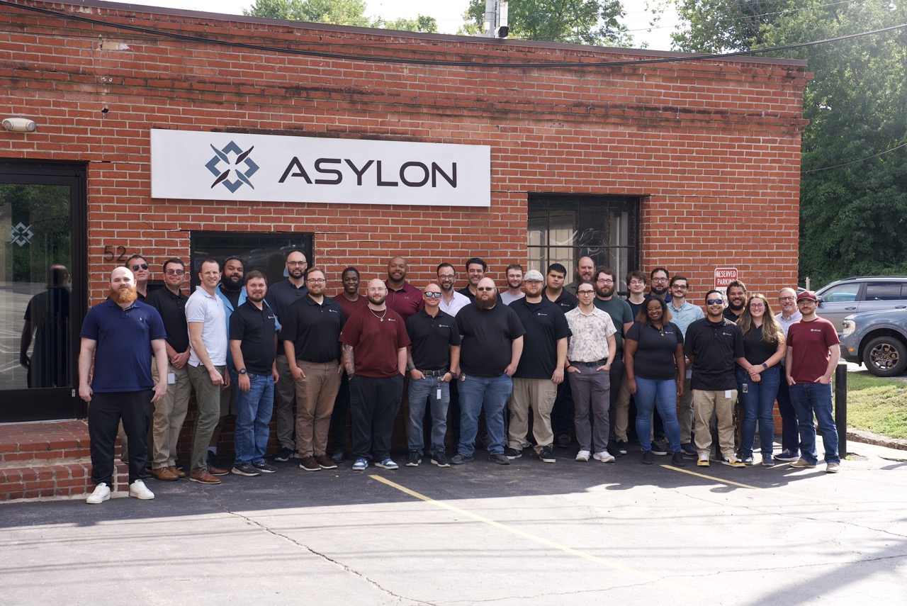Staff of Asylon Robotics pose for group photo outside their headquarters building.