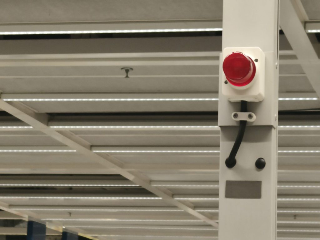 Red industrial strobe alarm light mounted inside a facility.