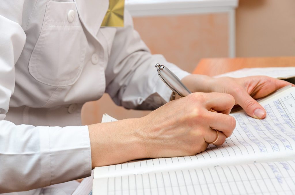 Person handwriting a log entry on a paper form, representing manual patrol records.