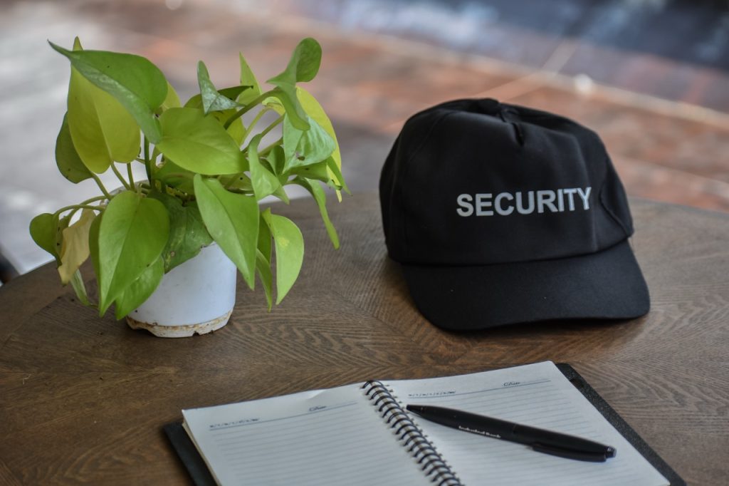 Security guard notebook and cap on a desk used for patrol documentation and incident reporting. 