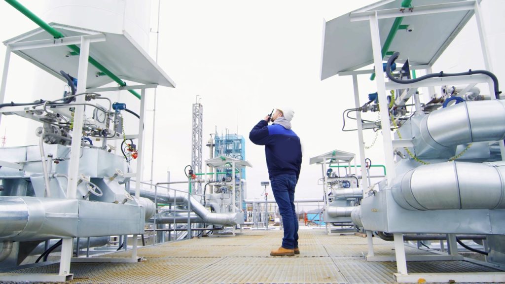 Manufacturing employee inspecting industrial processing equipment at a production facility. 