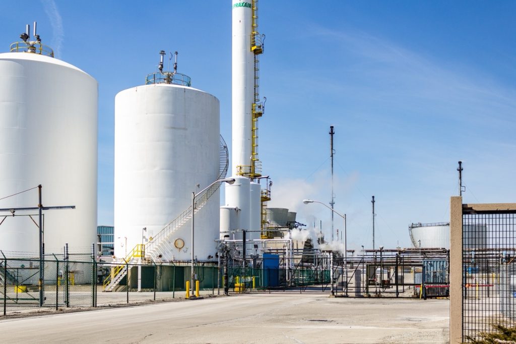 Two large, cylindrical storage tanks dominate the layout of a chemical facility, connected with piping.
