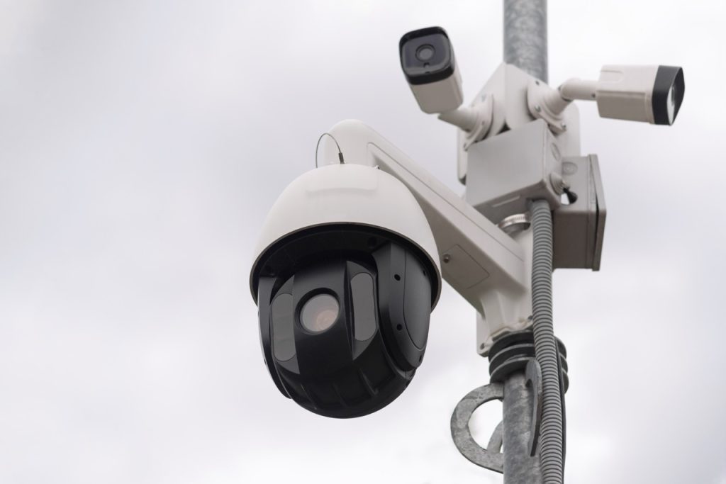 Low-angle view of three mounted and fixed security cameras on a pole at a water treatment facility