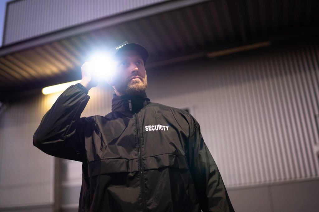 Security guard conducting a nighttime patrol outside an industrial energy facility. 