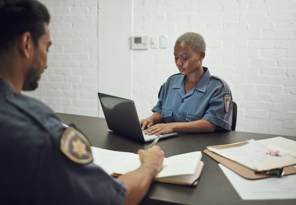 Airport security staff documenting patrol activity and incident records at a security operations center. 