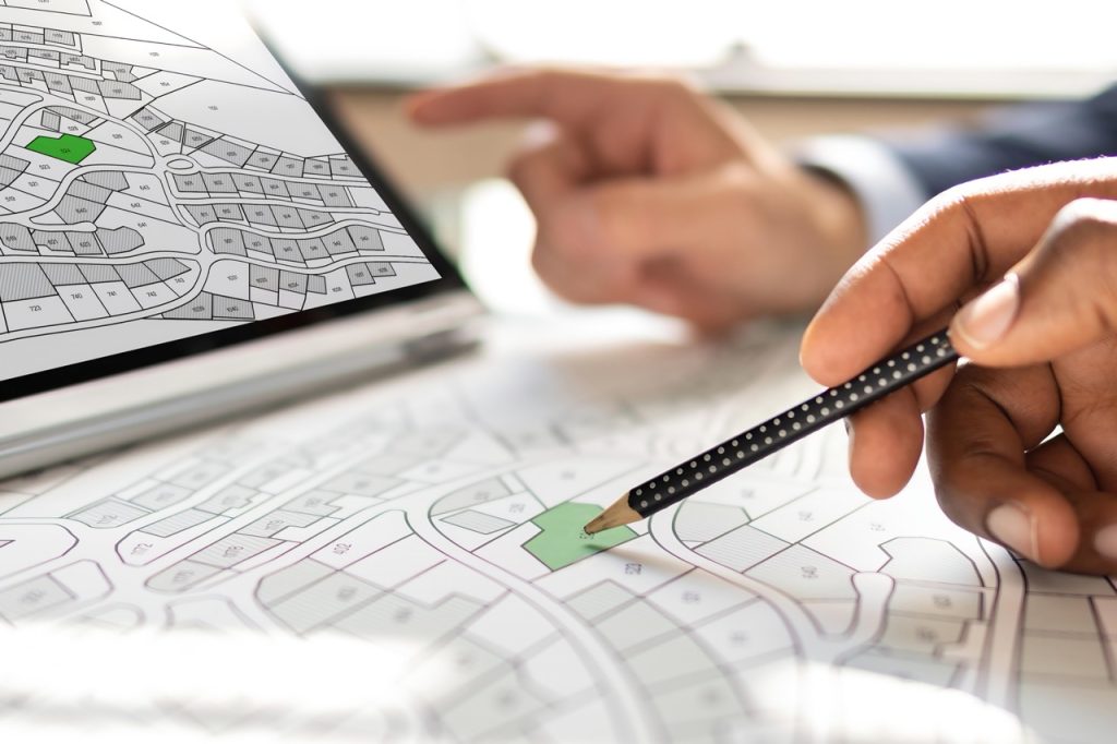 Security officer and private estate homeowner point to paper and digital maps of multiple properties.