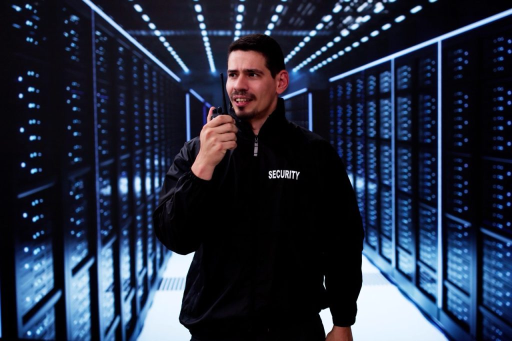Security officer communicating by radio inside a data center server room.