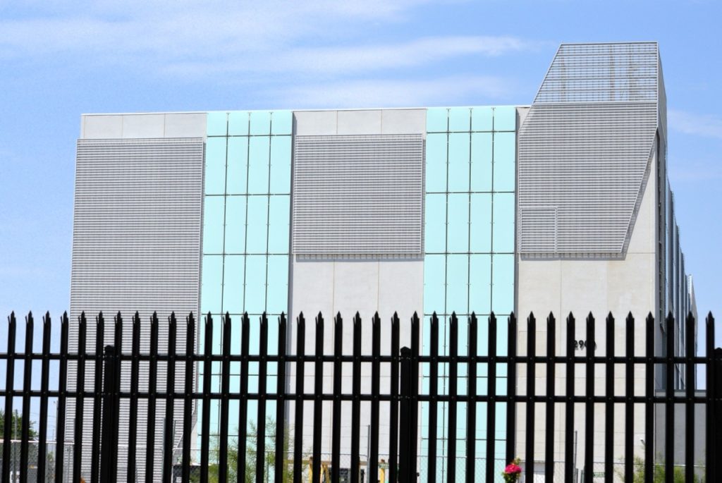 Modern data center building protected by a high-security perimeter fence.