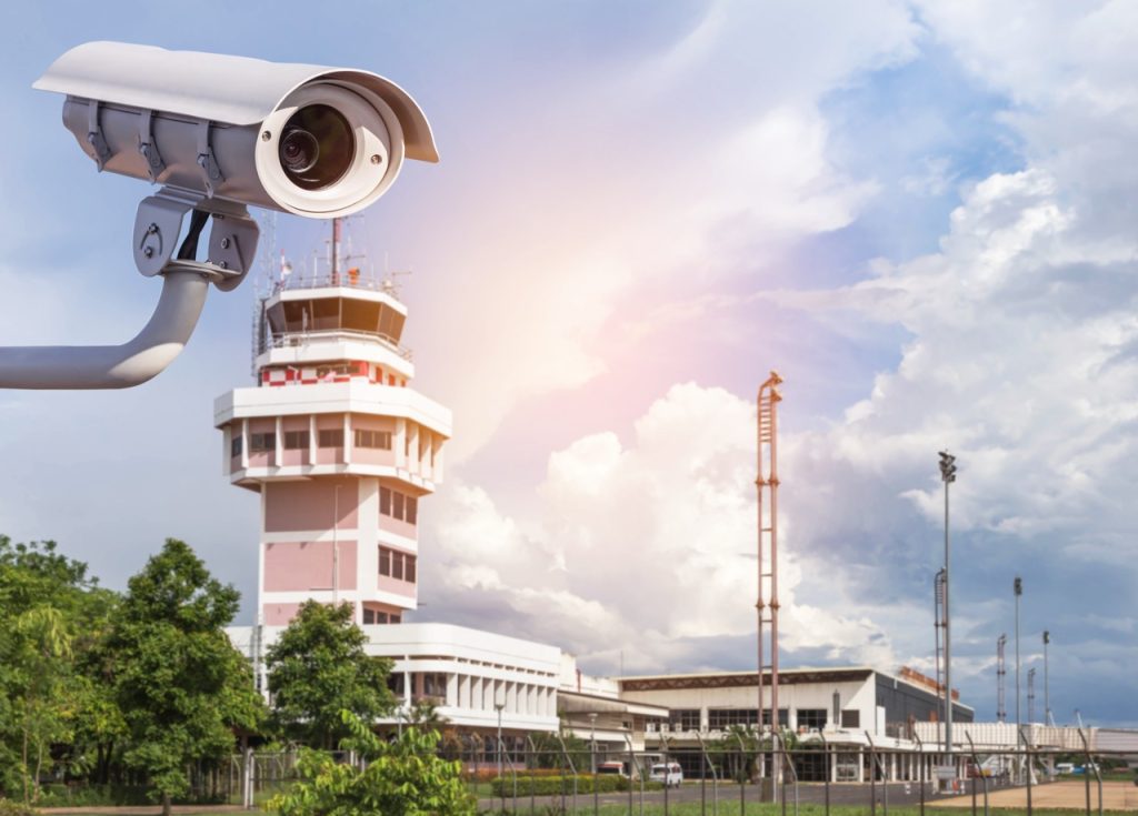 Airport security camera monitoring the perimeter fence and airfield near the control tower. 